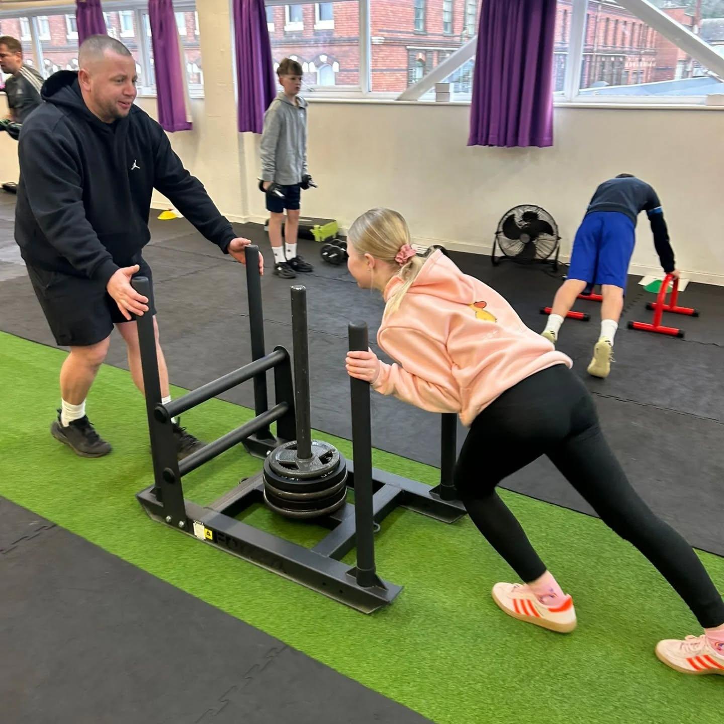 A young member training safely with a sled under coach supervision